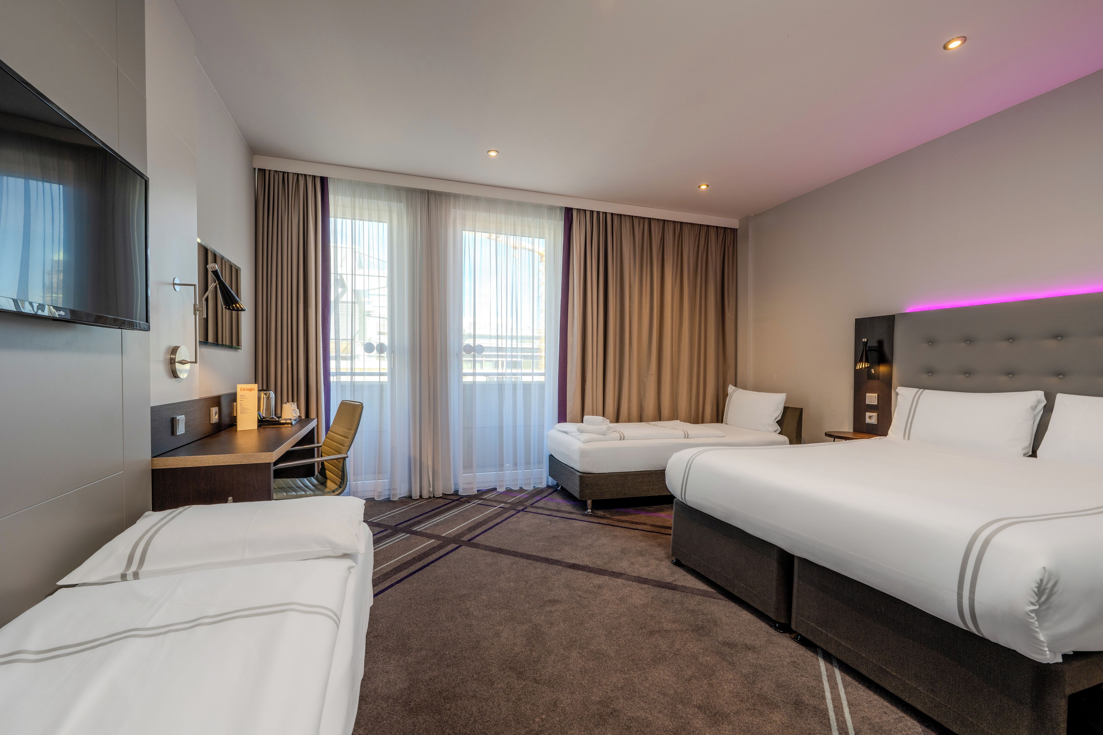 Habitación de hotel con dos camas, un escritorio, una silla, un televisor y un minibar.