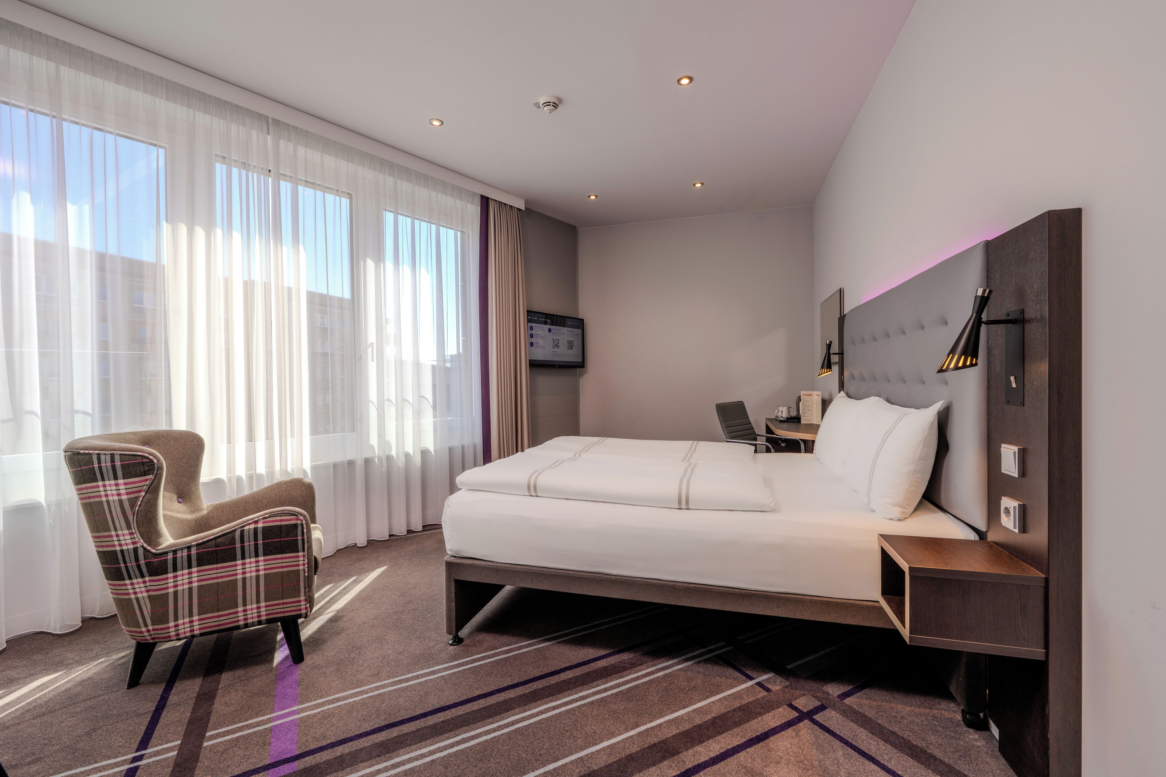 Une chambre d’hôtel avec un lit, une chaise, un bureau et un téléviseur.