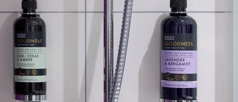 Two bottles of Goodness brand body wash on a wall.