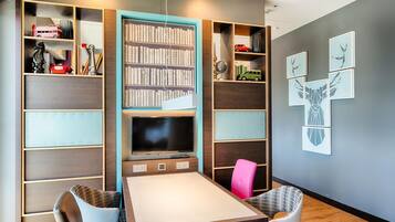Ein modernes Zimmer mit Fernseher, Bücherregalen und einem Essbereich.