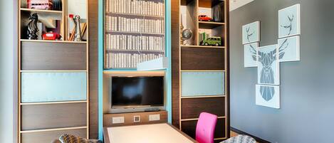 A modern room with a TV, bookshelves, and a dining area.