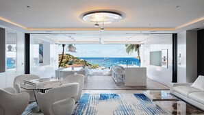 Un interior moderno con vistas al mar, que incluye un comedor, una cocina y una sala de estar con un televisor grande.
