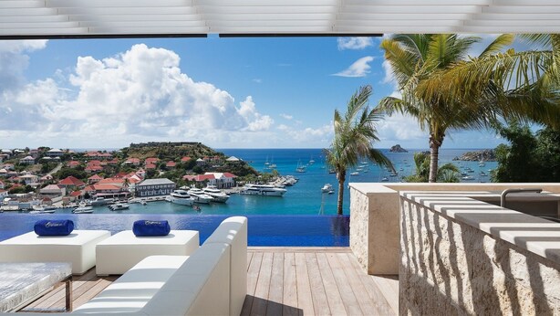 Una piscina infinita con vistas a un pueblo costero y un puerto deportivo.