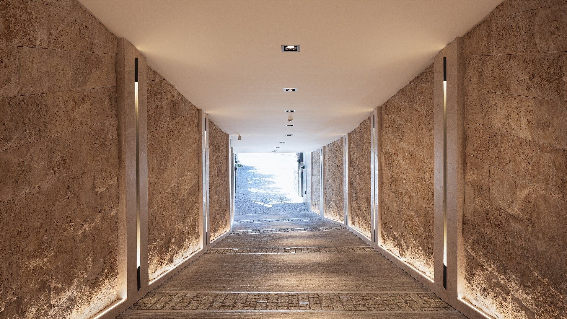 A hallway with a stone wall on one side and a glass wall on the other, leading to a view of a mountainous landscape.