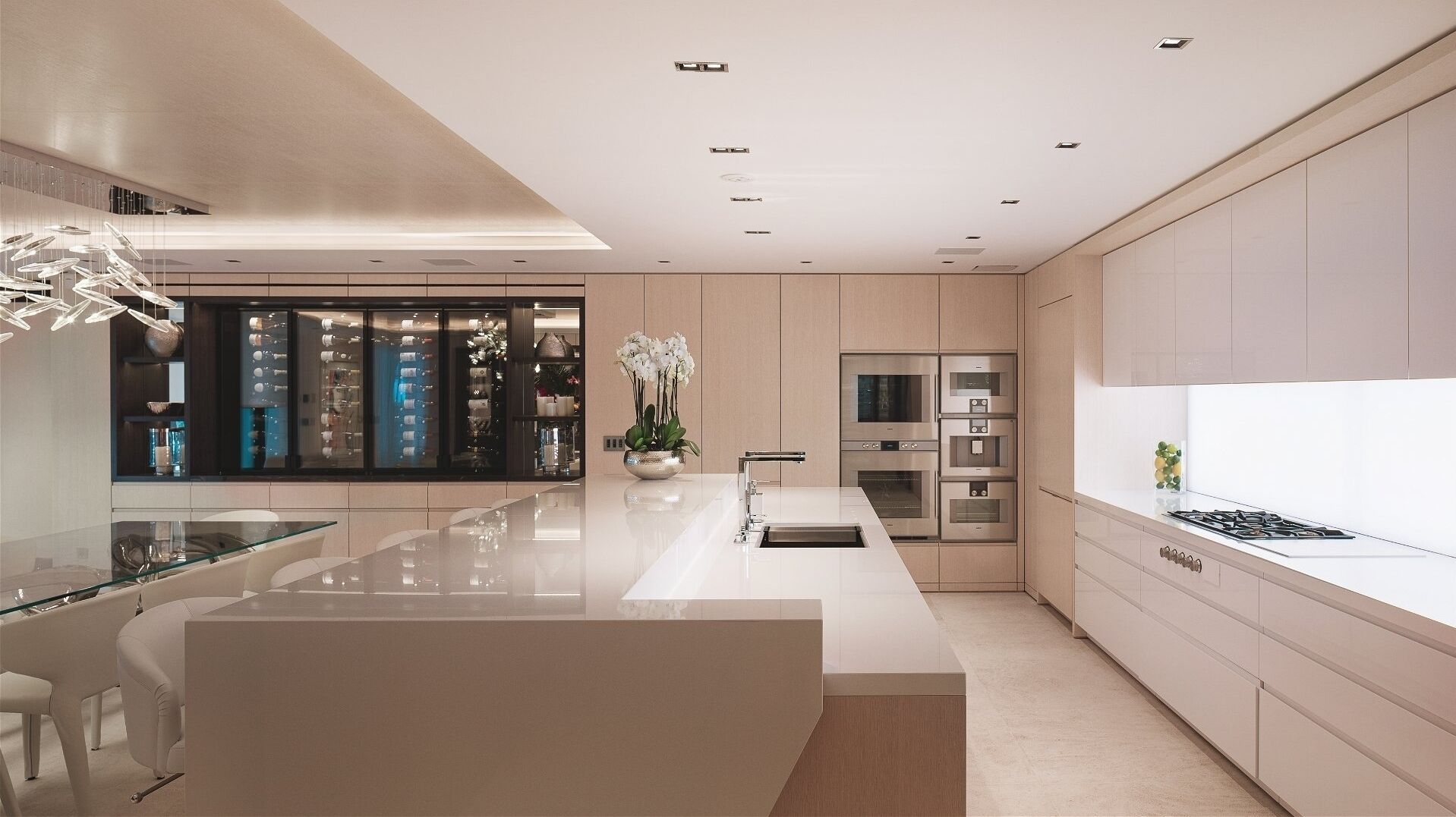 A modern kitchen with a central island, stainless steel appliances, and a glass dining area.