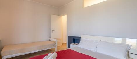 A bedroom with a bed, a bench, a bedside table, and a wall-mounted light.
