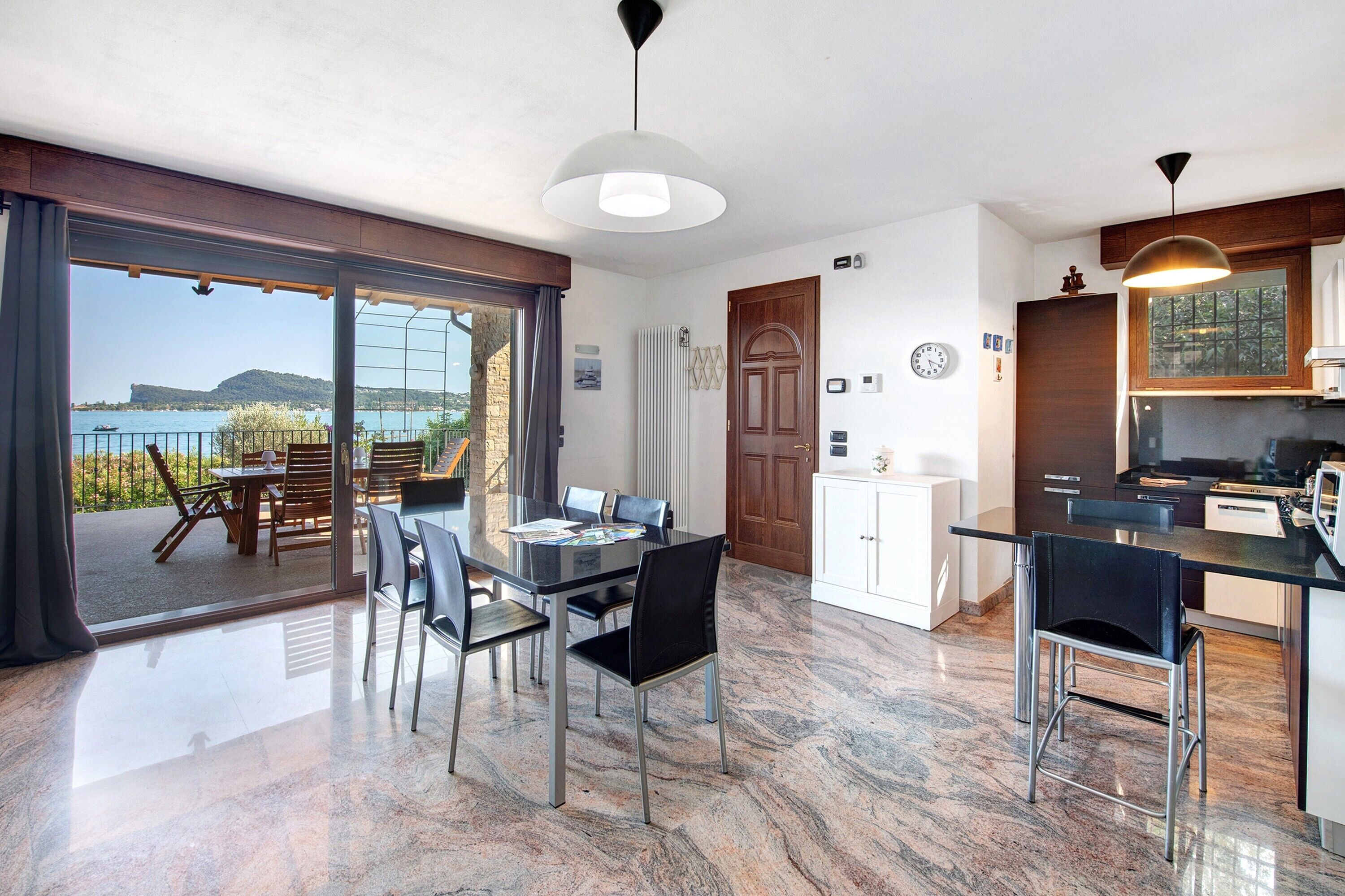 Une cuisine moderne avec vue sur la mer, un coin repas avec une porte vitrée et une grande fenêtre.