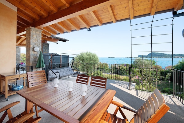 Une table en bois avec des chaises, un canapé et une vue sur la mer.