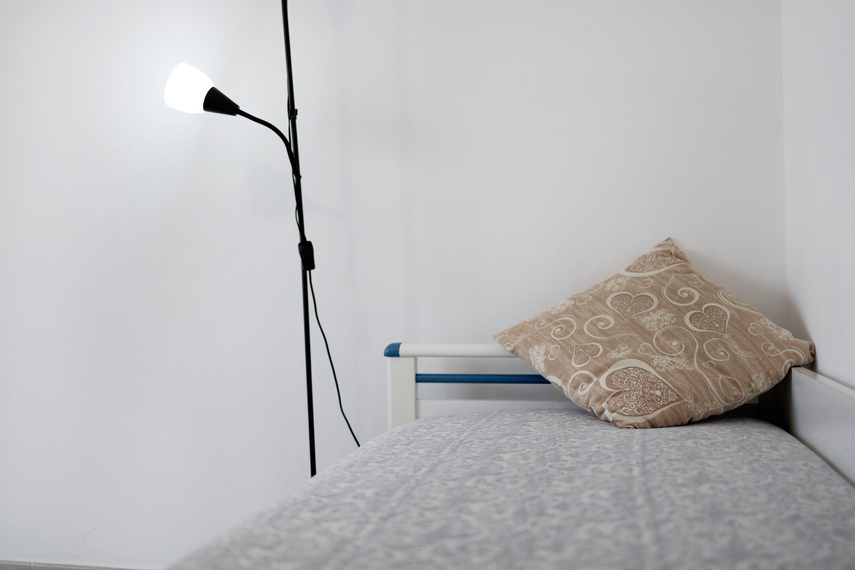 A bed with a patterned bedspread, a decorative pillow, and a bedside lamp.