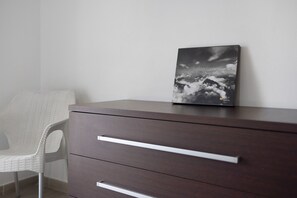 Une commode en bois foncé, sur laquelle est posée une photo encadrée.