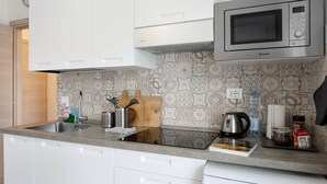 Una cocina con armarios blancos, microondas, fregadero y salpicadero con diseño.