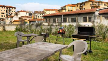 Eine Außenpatio mit Grill, Stühlen und einem Tisch.
