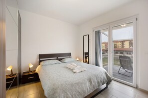 Une chambre à coucher avec un lit, des lampes de chevet, un miroir et un balcon avec une chaise.