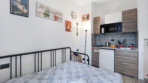 Une chambre à coucher de taille réduite, comprenant un lit, une petite table de chevet, une commode et une horloge fixée au mur.