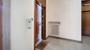 Un couloir avec une porte en bois, un radiateur et un paillasson.