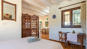 Un dormitorio con cama, escritorio, silla, ventana y un separador decorativo.