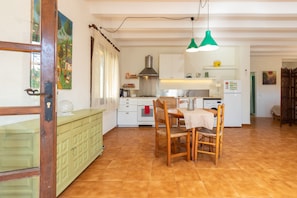 Una cocina con mesa, sillas, estufa y refrigerador.