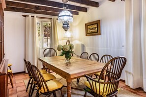 Ein Esszimmer mit Holztisch, sechs Stühlen, einer Chandelierleuchtre, einer Blumenvase und einem gerahmten Bild an der Wand.