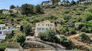 Une propriété située sur une colline, dotée d’une piscine, de murs en pierre et d’une variété de plantes.