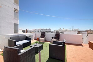 Eine Dachterrasse mit Gartenmöbeln, einer kleinen Pflanze und freiem Blick auf die Stadtlandschaft.