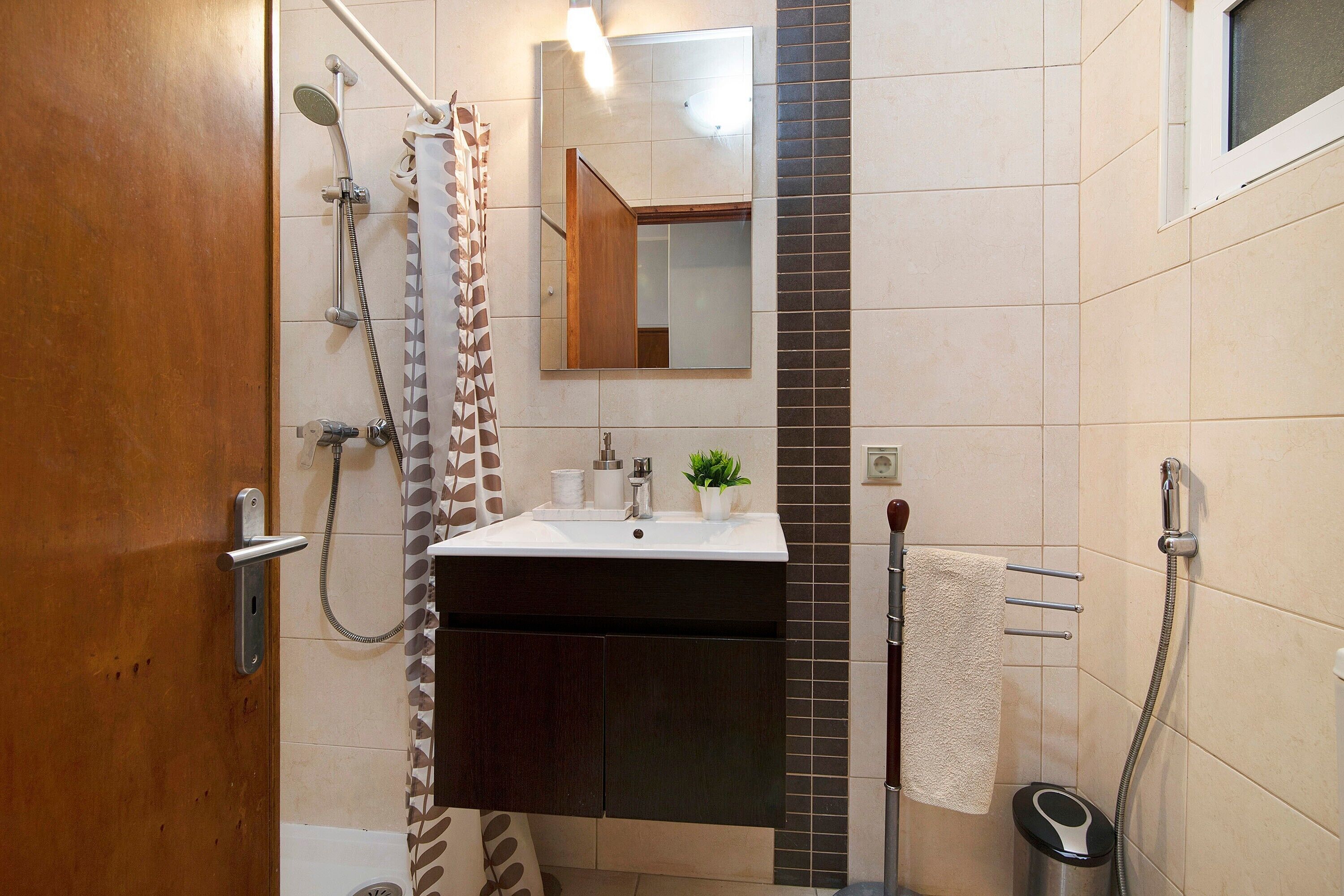 Ein Badezimmer mit Dusche, Waschbecken und Spiegel.