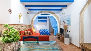 A room with a glass table, red sofa, and a view through an archway to another room.