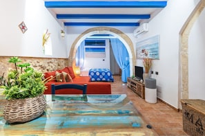 A room with a glass table, red sofa, and a view through an archway to another room.