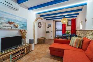 Una sala de estar con televisor, sofá, un cuadro y un reloj.