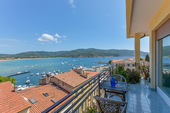 A balcony with a view of a marina and distant hills.