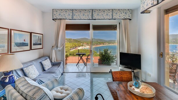 Un salon comprenant un canapé, une table, un téléviseur et un balcon avec vue sur la mer.