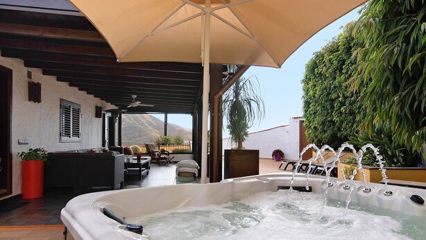 A hot tub with water jets, a patio area with outdoor furniture, and a view of mountains. - Holiday Home 'La Suerte' with Sea View, Wi-Fi and Air Conditioning (Agaete)