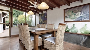A dining area with a wooden table and wicker chairs, a ceiling fan, and a painting on the wall. - Casa Los Jazmines with Pool & Jacuzzi – Sea Views, Wi-Fi, Air Conditioning (Agaete)