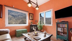 A room with a wooden table, a green cabinet, a bookshelf, and a large window with a mountain view. - Casa Los Jazmines with Pool & Jacuzzi – Sea Views, Wi-Fi, Air Conditioning (Agaete)