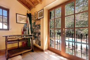A room with a wooden bookshelf, a window with a view of a pool, and a door with a glass panel.