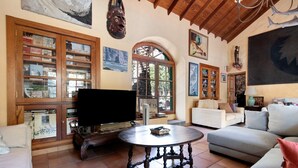 A living room with a television, a round table, a sofa, and a bookshelf. - "La Casa Del Molino De Viento" with Mountain Views, Private Heated Pool and Wi-Fi (Agaete)