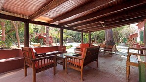A covered outdoor seating area with wooden furniture and a view of a garden. - "La Casa Del Molino De Viento" with Mountain Views, Private Heated Pool and Wi-Fi (Agaete)