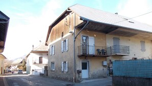 A street with buildings, including a two-story building with a balcony and a door marked "CINQ".