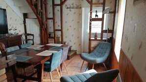 A dining area with a wooden table and chairs, a staircase, and a window with a view.