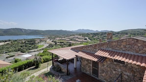 A stone building with a tiled roof overlooking a coastal landscape with a body of water and hills. - Villa Maria - 3bdr with 2 bathrooms (Palau)