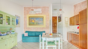 A kitchen with a dining table, chairs, a green cabinet, a blue sofa, and a painting on the wall. - Villa Maria - 3bdr with 2 bathrooms (Palau)