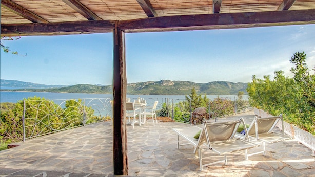 A stone patio with outdoor seating and a view of a lake and mountains. - Villa Maria - 3bdr with 2 bathrooms (Palau)