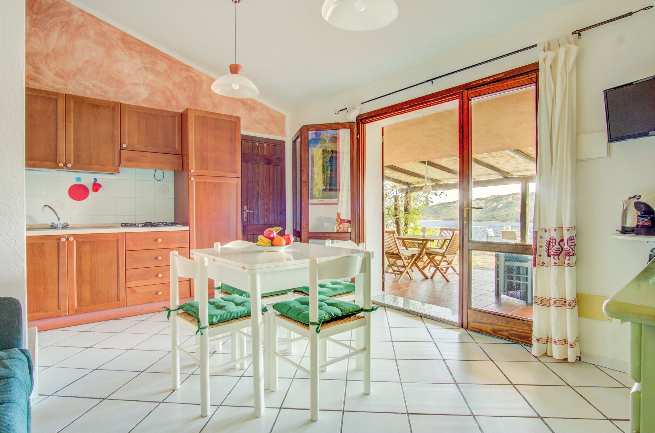 A kitchen with wooden cabinets, a white table with chairs, and a dining area with a view.