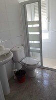 Un baño con inodoro, lavamanos y zona de ducha.