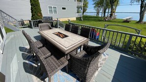 A deck with a table and chairs, overlooking a lake. - Lakefront home, large firepit patio, Game room! (Brewerton)