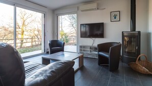Un salon moderne doté d’une cheminée, de grandes fenêtres et d’un téléviseur à écran plat.