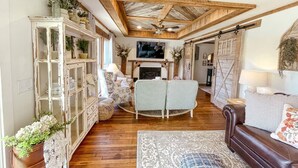 Un salon chaleureux avec une cheminée, un canapé, une table basse et un meuble.