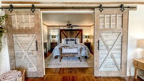 Une chambre à coucher avec un lit, un plancher en bois et une porte coulissante de style grange.