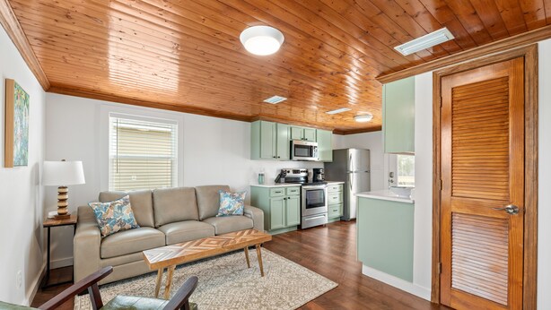 A cozy living room with a sofa, coffee table, and a wooden ceiling. - Cozy Cottage in the Heart of Gulf Shores (Gulf Shores)