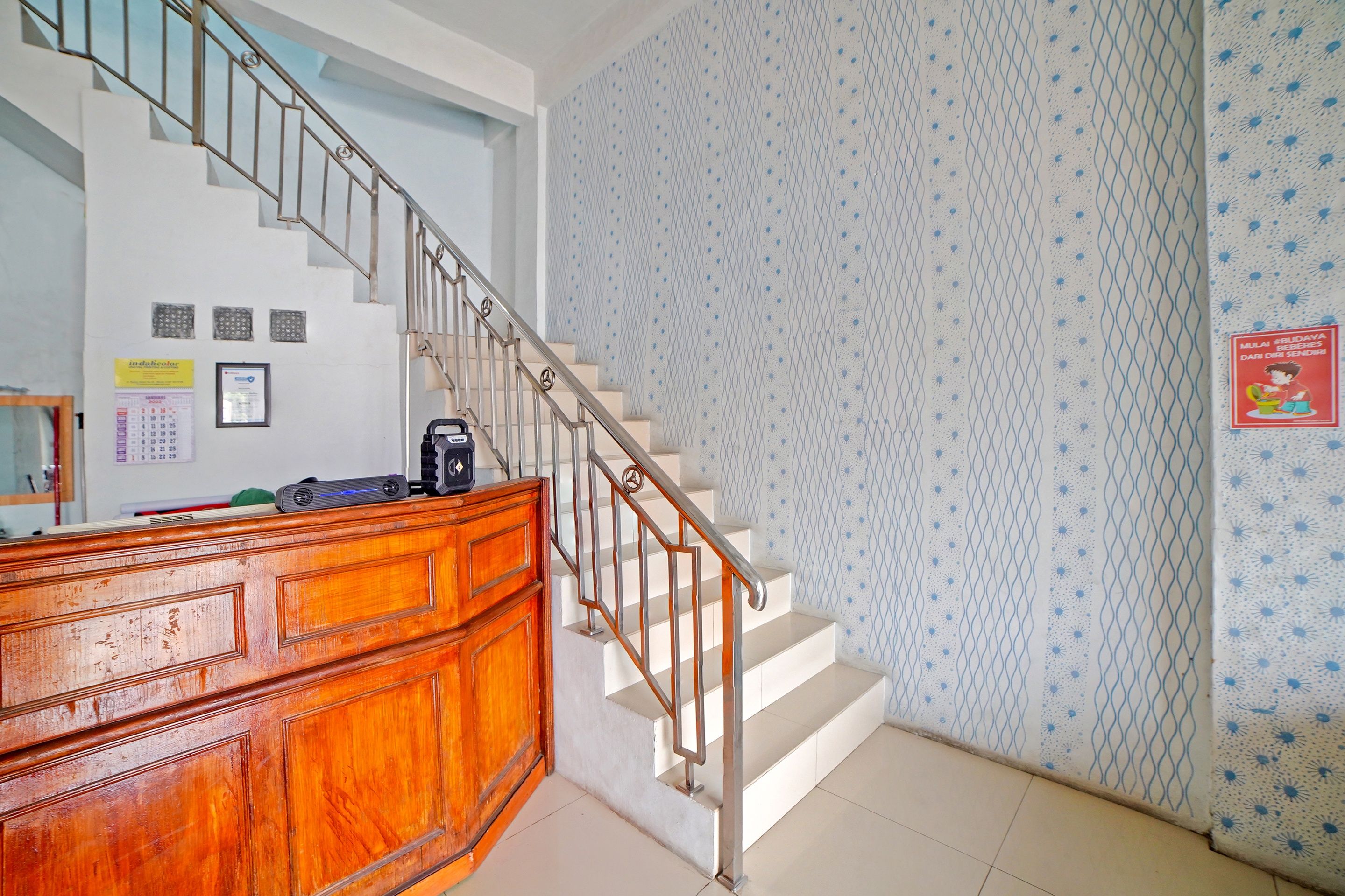 A staircase with a metal railing leading to a landing with a wooden desk and a calendar.