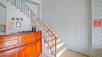 A staircase with a metal railing leading to a landing with a wooden desk and a calendar.